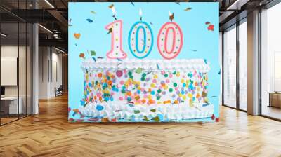 Colorful tasty birthday cake with candles shaped like the number 100. Pastel blue background. Wall mural