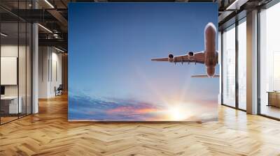 Commercial airplane flying above dramatic clouds during sunset. Wall mural