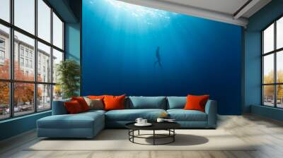 Freediver Swimming in Deep Sea With Sunrays. Young Man DIver Eploring Sea Life. Wall mural