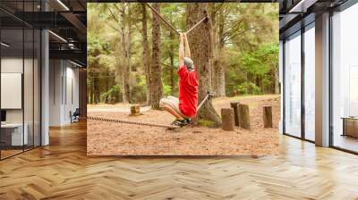 Teenager boy hanging between two ropes in the forest Wall mural