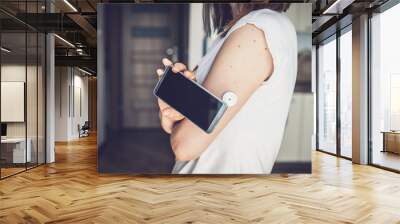 Woman checking glucose level with new technology remote sensor and mobile phone, sensor checkup glucose levels without blood. Diabetes treatment. Wall mural