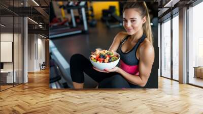 a young fit woman holding a bowl of fresh fruits at the gym, healthy lifestyle and diet, meal plan Wall mural