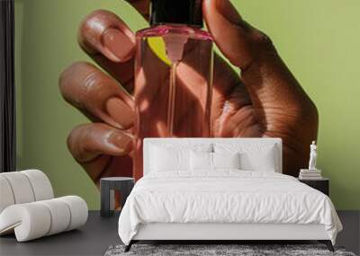 close-up manicured black female hand holding a spray bottle of perfume or serum, light green background Wall mural