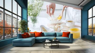 close-up of a woman mixing natural ingredients for a homemade facial scrub in a bright, cozy kitchen Wall mural