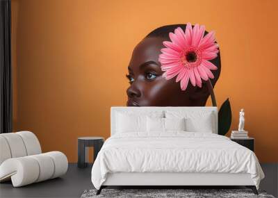 portrait of bald buzz cur black woman with pink flower, on orange background Wall mural