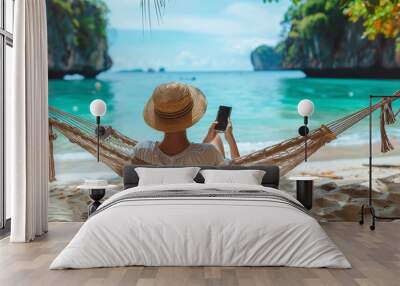 rear view of man traveler with mobile phone relax in hammock on summer beach Thailand, vacations Wall mural