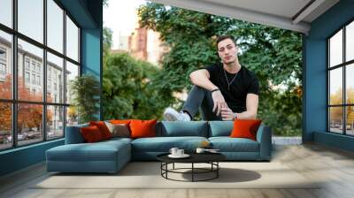 Young caucasian man wearing black t shirt and jeans. Fashion male model wearing casual clothing outdoors. Wall mural