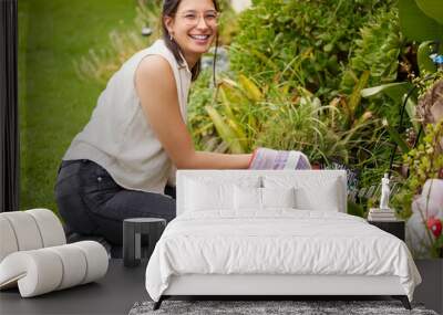 A peaceful heart, two green thumbs. Portrait of a smiling woman kneeling while doing some gardening in the backyard. Wall mural