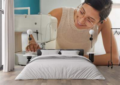 Just a woman who loves sewing. a young woman using a sewing machine in her workshop. Wall mural