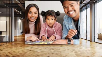 Puzzles are important for mental development. Shot of young parents helping their daughter build a puzzle. Wall mural