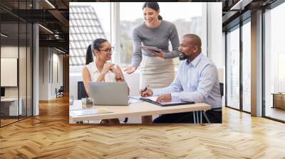 You guys have got this. Cropped shot of three corporate businesspeople having a meeting at a desk in their office. Wall mural