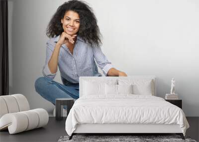 Portrait of a beautiful african woman sitting on gray background Wall mural