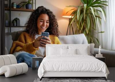 Latin girl sitting on couch using phone in living room at home. Relaxed happy young woman holding mobile cellphone technology doing shopping, communicating online, watching social media, Generative AI Wall mural