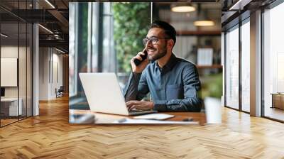 Young happy busy latin businessman talking on phone using laptop computer in office. Smiling hispanic professional businessman manager making call on mobile telephone sitting at work desk,GenerativeAI Wall mural