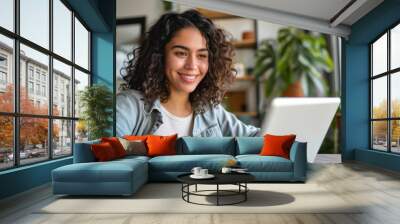 Young happy latin woman, smiling curly casual girl student using tablet and laptop elearning or working at home online looking at tab technology device sitting at table in living room, Generative AI
 Wall mural