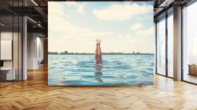 Summer feelings. Woman diving into water upside down with legs above surface. Wall mural