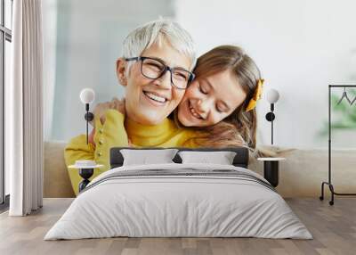 grandchild family child grandparent grandmother book reading elderly granddaughter girl happy together read learning education story fun leisure teaching storytelling senior smiling kiss hug Wall mural