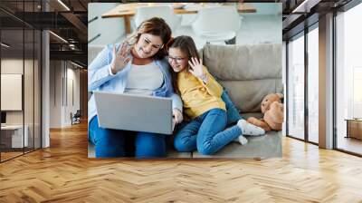 Mother and daughter wave to webcam on laptop Wall mural