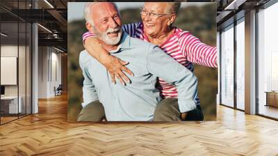 woman man outdoor senior couple happy lifestyle retirement together smiling love piggyback active mature Wall mural