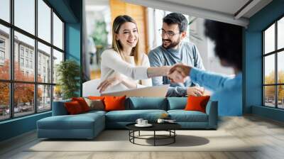 young couple shaking hands deal contract real estate investment Wall mural