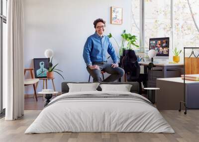 Cheerful businessman sitting on stool in light office Wall mural