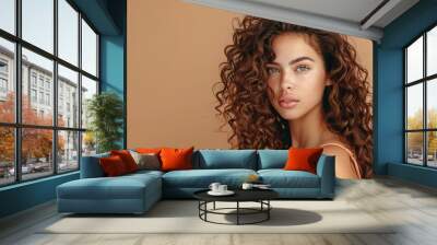 Young woman with curly hair on beige background. Studio portrait. Beauty and hair care concept. Design for poster, banner. Wall mural