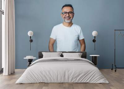 Smiling man in white t-shirt and jeans against gray background. Casual fashion concept. Wall mural