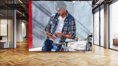 Young man using tablet pc touch in a bicycle Wall mural