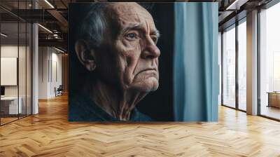 An elderly man gazes pensively out of a window during late afternoon, deep in thought, with warm sunlight illuminating his contemplative expression. Wall mural