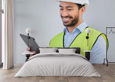 Construction worker, engineer and happy man in studio with tablet and helmet safety on white background. Smile, internet and contractor or architect in online planning for project management in India Wall mural