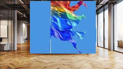 rainbow flag flying in the wind against a blue sky Wall mural