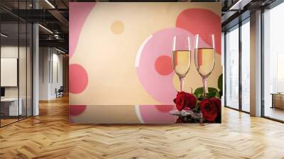 Champagne glasses, red roses in front of pink, beige background Wall mural