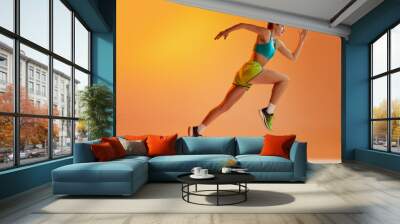 Athlete in motion. Young fitness sportive girl in sports uniform running, training isolated over yellow background in neon light. Dynamic movements, running technique. Wall mural