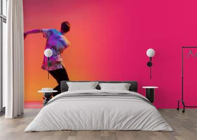 Back view of young stylish man dancing hip-hop isolated over colorful gradient background in neon light. Flyer Wall mural