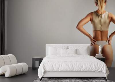 Banner. Woman's lower back and buttocks, showcasing her toned and fit physique in gray ribbed underwear against grey studio background. Concept of beauty and fashion, female health, anti-cellulite Wall mural