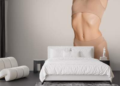 Beautiful female body in nude color underwear over grey background. Wall mural