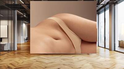 Close-up cropped image of slim female belly, buttocks in underwear isolated over beige studio background. Women's health Wall mural