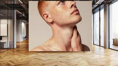 Close-up portrait of handsome young red-haired man posing isolated over grey studio background. Thoughtful look Wall mural