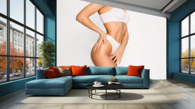 Close-up slim tanned female body in underwear over white background. Wall mural