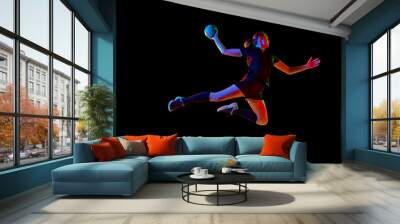 Determined female athlete practicing handball moves with concentration and dedication against black background in neon light. Concept of sport and action, dynamic, victory, championship, ad. Wall mural