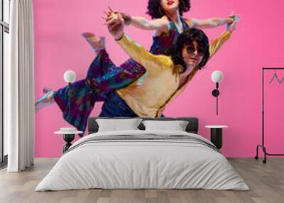 Disco dancing couple in dynamic lift pose vibrant retro style outfit against gradient pink studio background. Energetic moves. Concept of American culture, 1970s, music, comparisons of eras. Wall mural