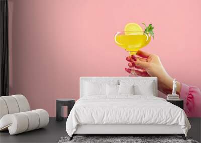 female hand holding vibrant citrus, tropical cocktail against pastel pink background with negative space yo insert text. Concept of alcohol, drink, party, degustation, holiday. Copy space for ad Wall mural