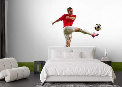 Full length portrait of professional soccer player kicking ball against white background on green grass. Looks extremely motivated. Wall mural