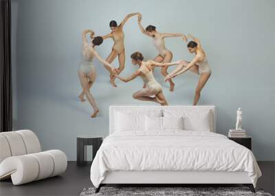 Group of young girls, ballet dancers performing, posing isolated over grey studio background. Circle movements Wall mural