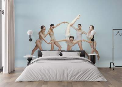 Group of young girls, ballet dancers performing, posing isolated over grey studio background. Holding hands Wall mural