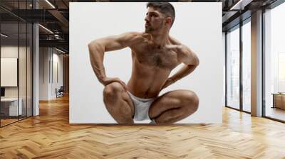 Handsome young muscular man posing shirtless over white studio background. Masculinity and strength Wall mural