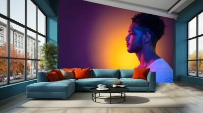 Portrait of a young african man at studio. High Fashion male model in colorful bright neon lights. Art design concept. Wall mural