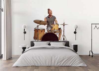 Portrait of funny emotive man playing drums, performing isolated over white background. Bass, rock music Wall mural