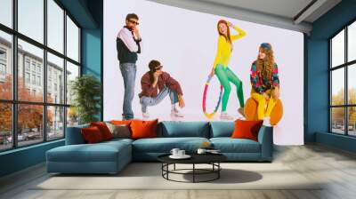 Portrait of stylish young people, boys and girls in bright clothes doing fitness, posing isolated over grey background Wall mural