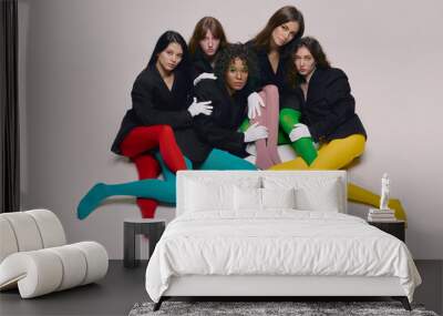 Portrait of young beautiful different women in black jackets and colored tights posing over grey background. Concept of beauty, freedom, emotions, fashion, modern style, weird people Wall mural